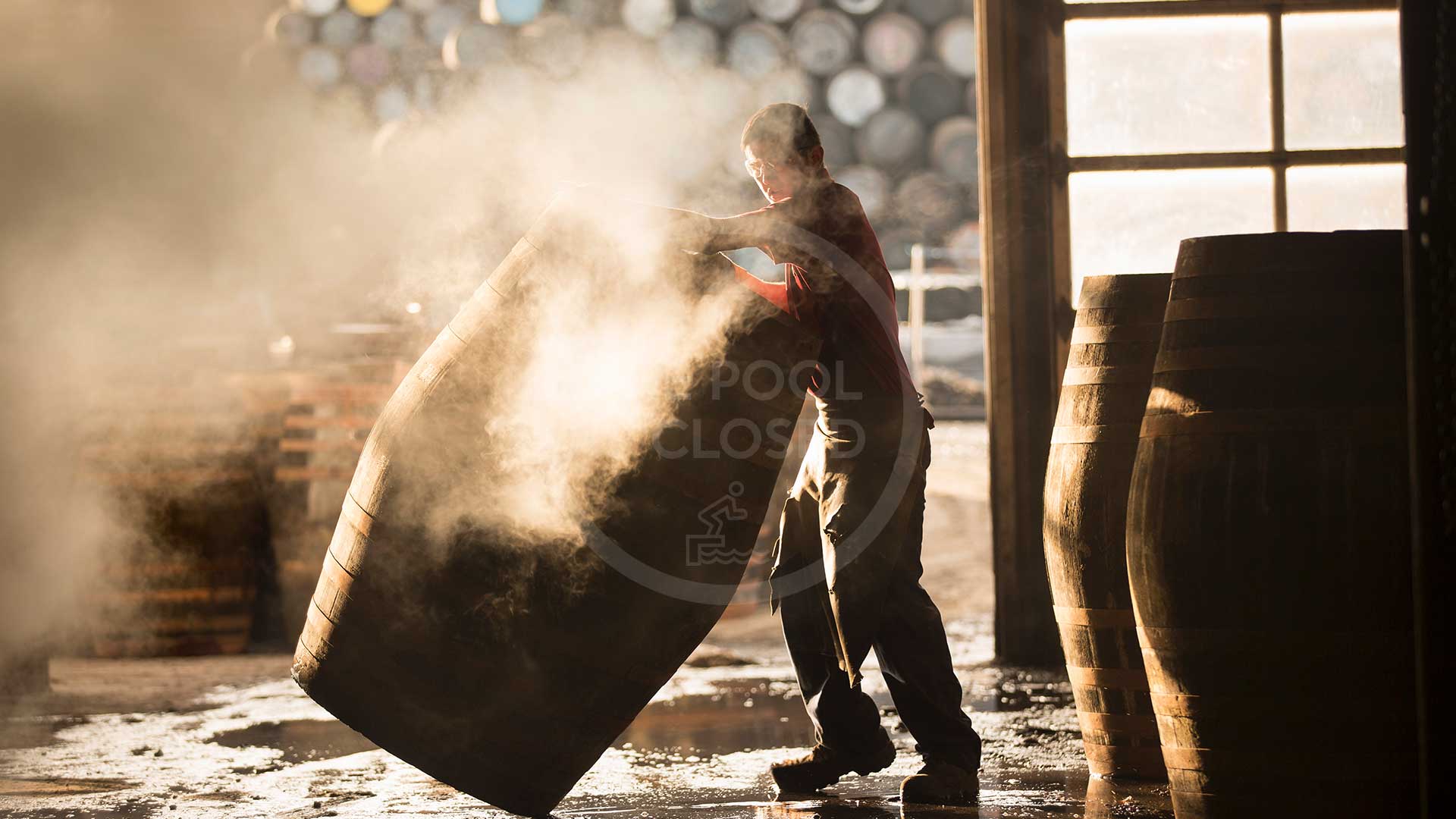 Male cooper working in cooperage with whisky casks