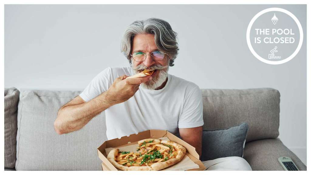 man eating pizza on his couch out of the delivery box